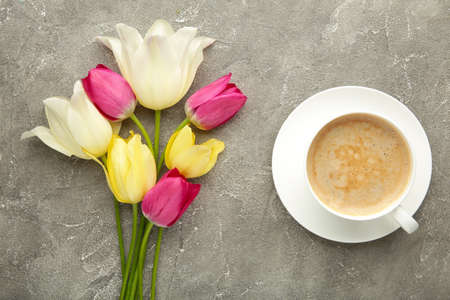 Cup of coffee with tulips on gray background with copy space. Top view.の写真素材