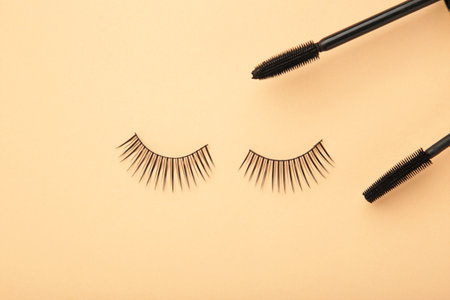 Black eyelashes and mascara on beige background. Top view. Beauty conceptの写真素材