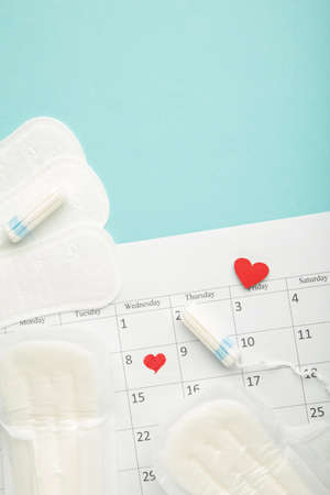 Menstruation calendar with cotton tampons and pads. Woman critical days, woman hygiene protection. Top view. Vertical photoの写真素材