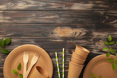 Eco friendly disposable dishes with green leaves on brown background. Zero waste, eco friendly, plastic free background. Top viewの写真素材