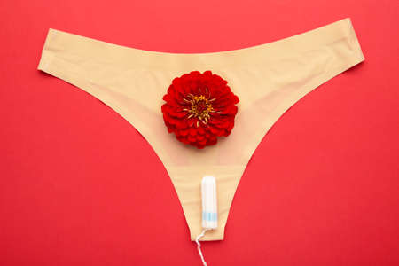 Women's panties with menstrual tampons on red background. Top view. Concept of critical days, menstruation, feminine hygiene. Top viewの写真素材
