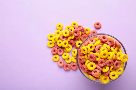 Multicolor cereals with fruity on purple background. Blank space for texts.