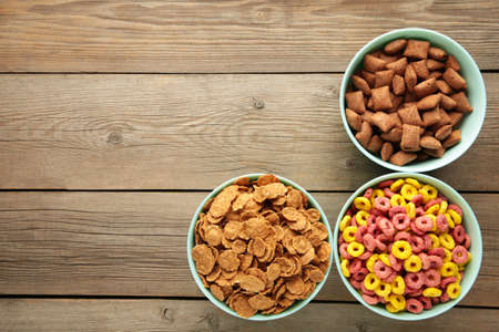 Variety of cereals in blue bowls, quick breakfast on gray wooden background. Top view