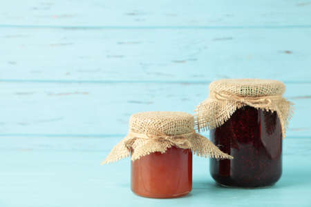 Glass jars with different kinds of jam on blue background. Top viewの写真素材