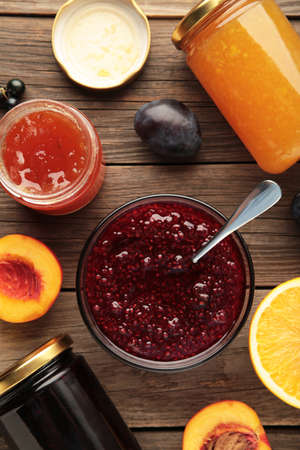 Assortment of jams, seasonal fresh berries and fruits on gray background. Vertical photo