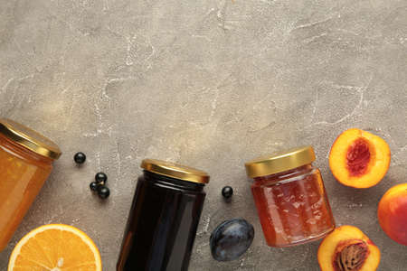 Homemade fruit jam in the jar with fresh fruit and berries on gray background.の写真素材