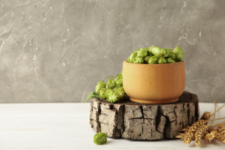 Wooden bowl with hops and wheat on white wooden background, space for text. Top viewの写真素材