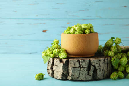 Wooden bowl with hops on blue wooden background, space for text. Top viewの写真素材