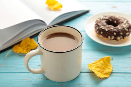 Donut, coffee cup and autumn leaves on blue background, top viewの写真素材