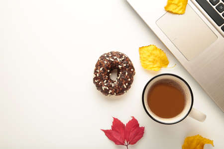 Donut, coffee cup and autumn leaves on white background, top viewの写真素材