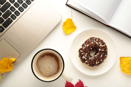Donut, coffee cup and autumn leaves on white background, top viewの写真素材