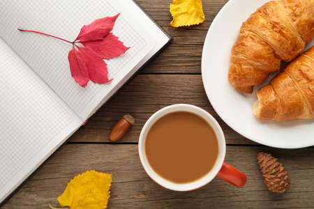 Hot coffee with croissant and autumn leaves on gray - seasonal relax concept. Top viewの写真素材