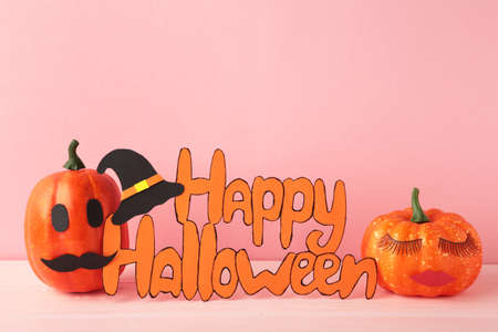 Inscription Happy Halloween with pumpkins on pink background. Top viewの写真素材