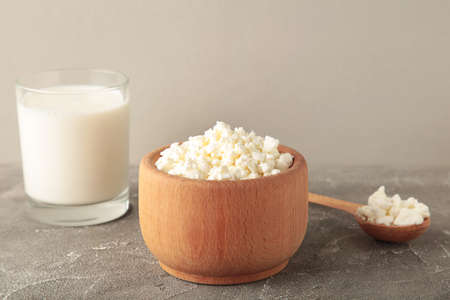 Cottage cheese for breakfast in wooden bowl on gray background. Top view