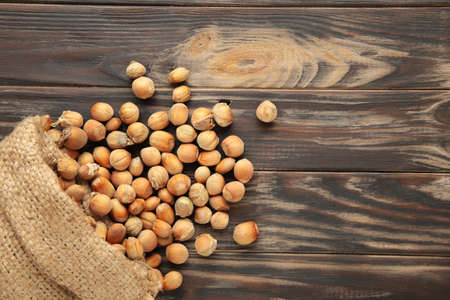 Hazelnuts, filbert in burlap sack on brown wooden backdrop. Hazelnut background, healty food. Top viewの写真素材