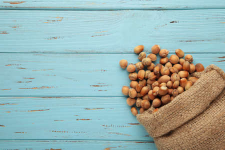 Hazelnuts, filbert in burlap sack on blue wooden backdrop. Hazelnut background, healty food. Top viewの写真素材