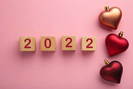Christmas background with red hearts and numerals 2022. New Year concept on pink. Top view
