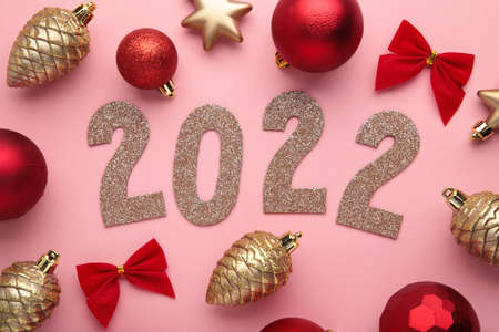 Christmas background with fir trees, fir cones and Christmas decorations and numerals 2022. New Year concept on pink. Top viewの写真素材
