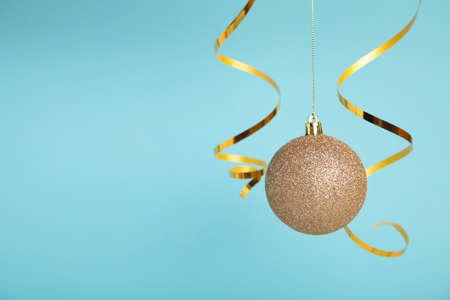 Golden christmas ball with ribbon on blue background with copy space. New Year 2022. Top viewの写真素材