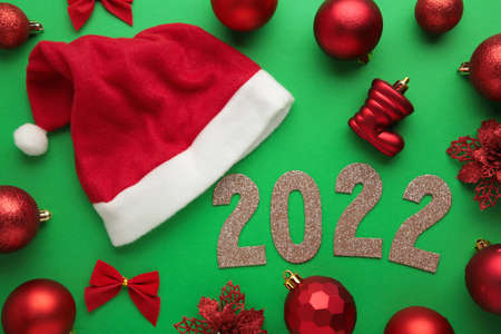 Happy New Years 2022. Christmas background with santa claus hats, christmas balls and numerals 2022....