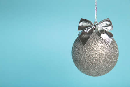 Glittering silver Christmas ball with bow on blue background. Top viewの写真素材