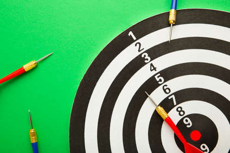 Dart board with blue and red darts on green background. Top view.