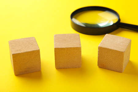 Wooden cubes with word SMM and magnifying glass on yellow background. Top view.の写真素材