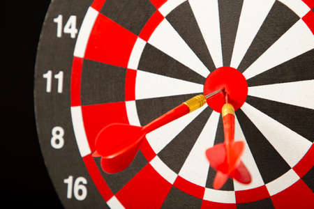 Dart board with darts on black background. Top view.