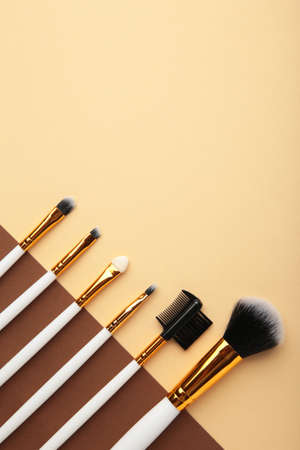 Various makeup brushes on brown and beige background with copy space. Top viewの写真素材