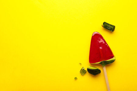 Red lollipop candy broken in pieces on yellow background. Top viewの写真素材