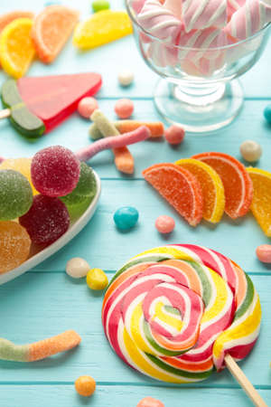 Colorful candies lollipops and jelly on blue background. Top view. Sweets with copy space. Vertical photoの写真素材