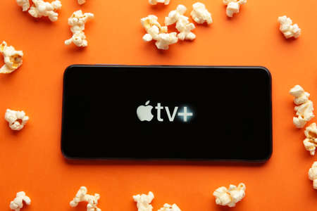 Nikolaev, Ukraine - November 20, 2021. Smartphone with Apple TV logo and popcorn on orange background. Top viewのeditorial素材