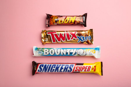 Snickers, Mars, Bounty and Twix chocolate bars on pink background. Top view. Nikolaev, Ukraine - December 19, 2021のeditorial素材