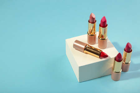 Mockup of different lipsticks on a white geometric podium on blue background. Background for branding and packaging presentation. Beauty and makeup product concept. Top viewの写真素材