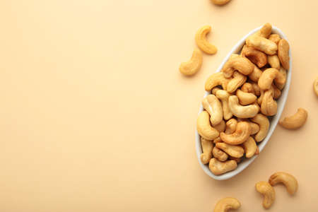 Cashew nuts on white plate on beige background.の写真素材