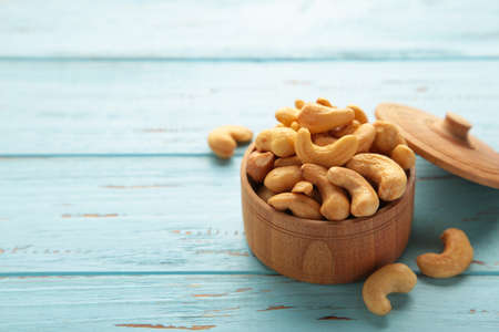 Cashew nuts on wooden bowl on blue background.の写真素材