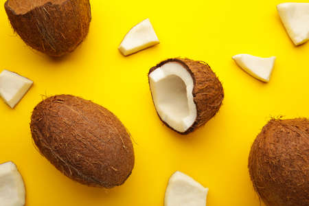 Coconut on a yellow background. Halves and whole coconuts.