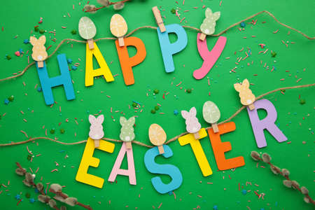 Inscription Happy Easter on green background, a rope with clothespins. The concept of postcards for...