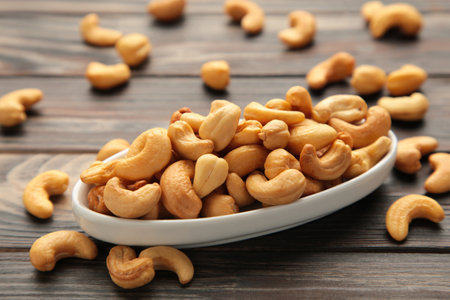 Cashew nuts on white plate on brown background with copy space.の写真素材