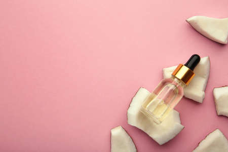 Coconut oil with coconut on pink background. Vertical photo