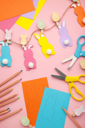 Easter bunnies handmade from colored paper, easy crafts for kids on a pink background. top view.の写真素材