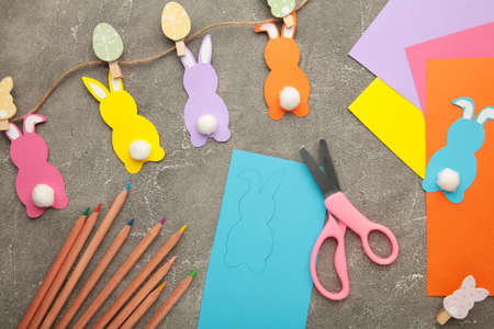 Easter bunnies handmade from colored paper, easy crafts for kids on a gray background.
