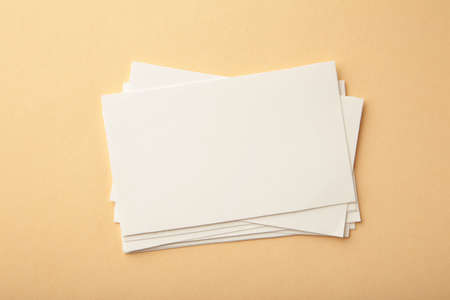 Blank white business cards on beige paper background. Mockup for branding identity. Template for...