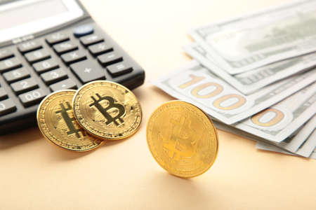 Bitcoin coin and cash with calculator on beige background. top view
