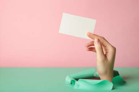 Female holding a credit card break through the paper. top view