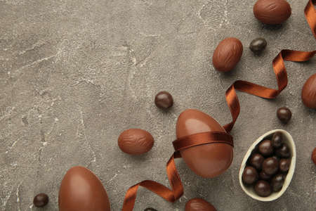 Easter composition with chocolate eggs and brown ribbon on gray background. top view