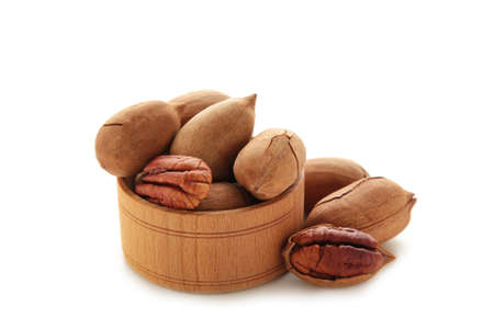 Fresh tasty pecan nuts on wooden bowl isolated on a white background. top view.