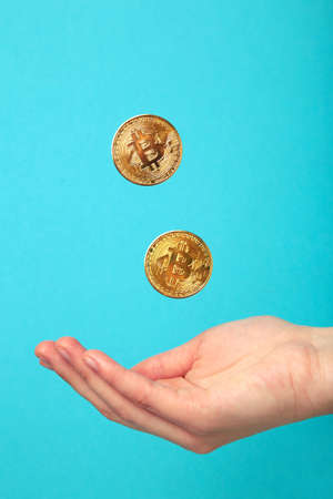 Golden bitcoins fall on hand on blue background. top viewの写真素材