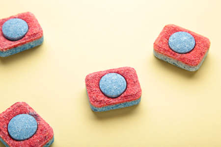 Red and blue tablets for dishwashing machine. Detergents for home hygiene. Dishwasher capsules on yellow background. top viewの写真素材