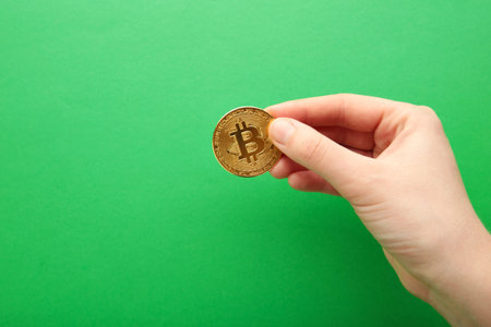 Female hand with coin of bitcoin on green background. top viewの写真素材